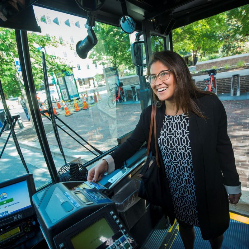 Una imagen fotográfica de un pasajero escaneando su tarjeta de transporte mientras aborda el transporte público.