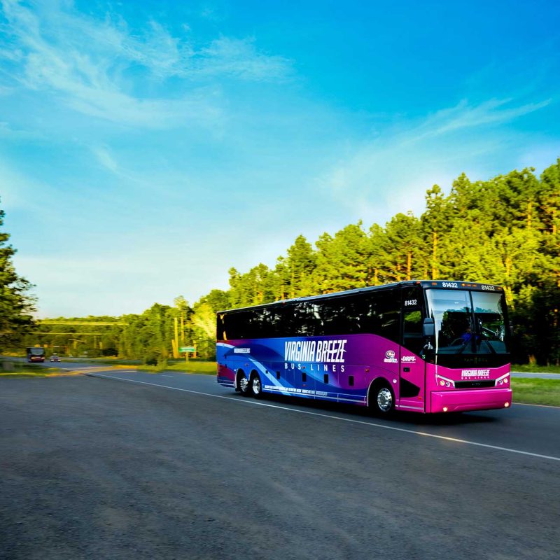 Autobús Virginia Breeze en la interestatal. Cielos azules y árboles de hoja perenne.