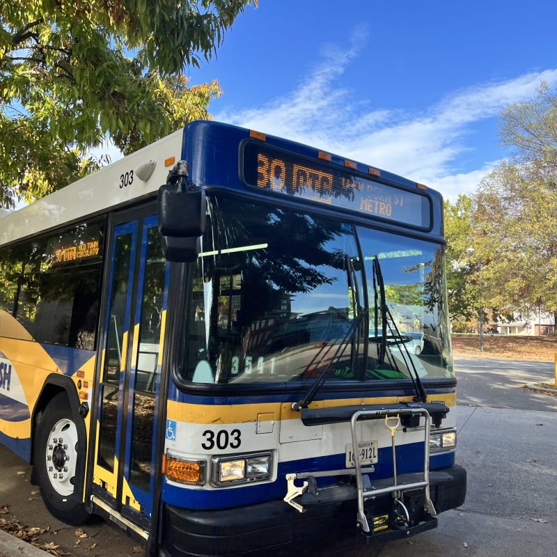 Una imagen fotográfica de un autobús público aparcado junto a una calle tranquila.